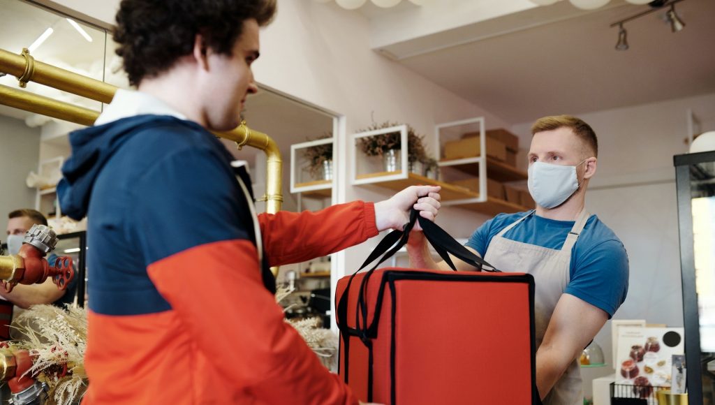 https://www.pexels.com/photo/man-in-a-face-mask-handing-over-a-thermal-bag-to-another-man-4393668/