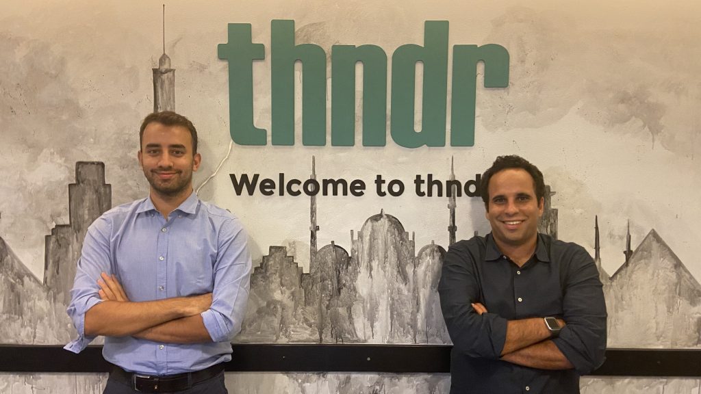 Founders of THNDR investment startup in front of THNDR logo