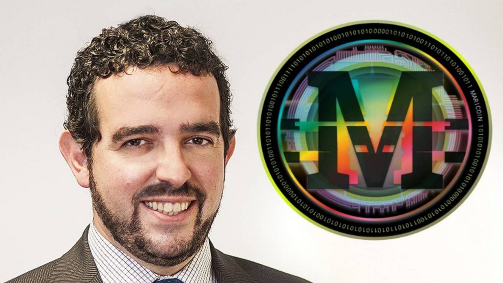 Maricoin CEO Francisco Álvarez Cano, 48, poses next to the world’s first LGBT+ cyptocurrency’s logo in Madrid, Spain. Photo: Supplied/Thomson Reuters Foundation/Handout by Fede Grau